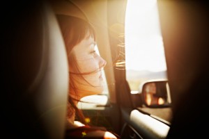 Woman with hair blowing looking out window of car